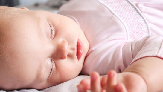 Baby asleep in side of a crib